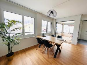 a dining room with a table and chairs and windows at New building with balcony closecentrefreeparkingsmarttv in St. Gallen