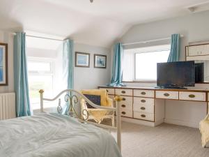 a bedroom with a bed and a dresser with a television at Hen Ysgol in Llanfaethlu