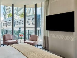 una camera da letto con TV a schermo piatto e 2 sedie di SLS LUX Brickell a Miami