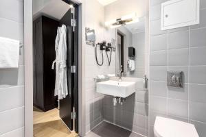a white bathroom with a sink and a toilet at Saga Hotel Oslo, WorldHotels Crafted in Oslo
