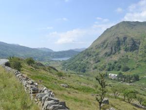 a long stone wall on a hill with a mountain at 4 Tan Y Bryn Terrace in Prenteg