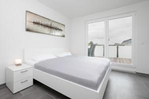 a white bedroom with a white bed and a window at Brenkenhagener Weg 4 Wohnung 7 in Grömitz