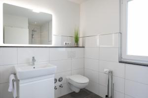 ein weißes Bad mit einem WC und einem Waschbecken in der Unterkunft Brenkenhagener Weg 4 Wohnung 7 in Grömitz