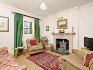 a living room with a fireplace and green curtains at Gardeners Cottage-uxt in Corsock