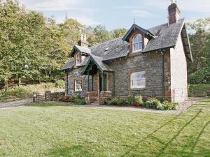 a small stone house with a grass yard at Gardeners Cottage-uxt in Corsock