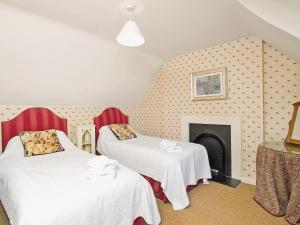 two beds in a room with a fireplace at Gardeners Cottage-uxt in Corsock