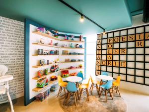 ポソス・デ・カルダスにあるibis Styles Poços de Caldasのテーブルと椅子、棚付きの壁が備わる客室です。