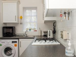 a kitchen with a stove and a washing machine at Beach Walk Cottage in Scarborough
