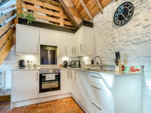 a kitchen with white cabinets and a clock on the wall at Pippin-uk41837 in Clevedon