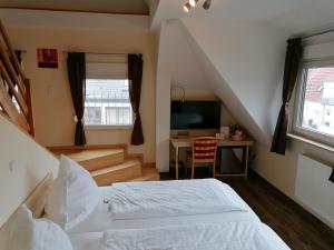 a bedroom with a bed and a desk with a television at Landgasthof Niebler in Adelsdorf