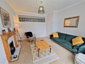 sala de estar con sofá verde y chimenea en Lovely Seafront Apartment with Garden, en Swansea