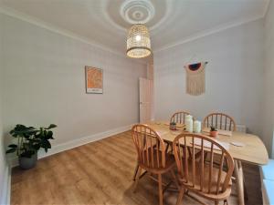 comedor con mesa de madera y sillas en Lovely Seafront Apartment with Garden, en Swansea