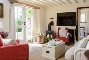 uma sala de estar com mobiliário vermelho e uma lareira em The Old Bakehouse Cotswold Cottage em Stonesfield
