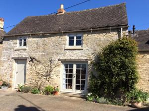 an old stone house with a white door at The Old Bakehouse Cotswold Cottage in Stonesfield