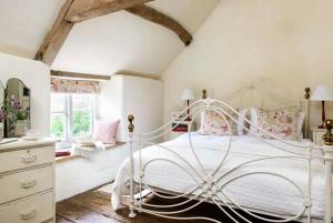 um quarto com uma cama branca e uma janela em The Old Bakehouse Cotswold Cottage em Stonesfield