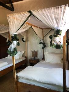 Msaranga的住宿－Rudi House，一间卧室配有两张床和一张天蓬床。