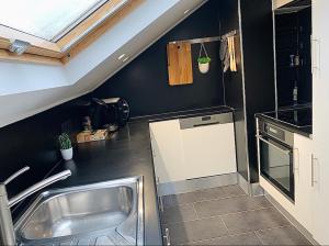 a kitchen with a stainless steel sink and black walls at Esch/Alzette city apartment in Esch-sur-Alzette