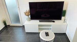 a television on a white cabinet with a stool at Esch/Alzette city apartment in Esch-sur-Alzette