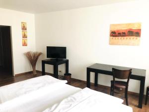 a room with two beds and a desk with a television at Apartment Rathausplatz - HOTEL FÜRSTENHOF in Kempten