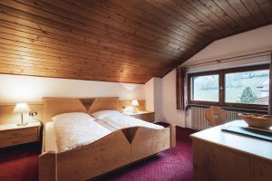 una camera con un grande letto e un soffitto in legno di Garnì Iosc a San Vigilio Di Marebbe