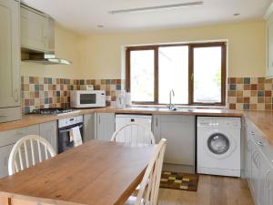 a kitchen with a table and a washing machine at The Coach House in Corney