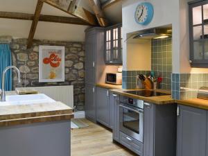 a kitchen with gray cabinets and a sink and a stove at The Carriage House in Belsay