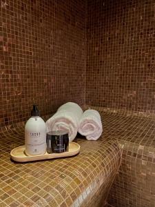 - une bouteille de savon et des serviettes sur le lit dans l'établissement L'Invitation au Voyage Hôtel- Espace Bien-être - Bar Lounge, à Honfleur