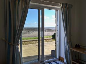 a sliding glass door with a view of the ocean at Limpet Cottage in Boulmer