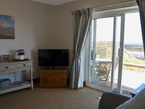 a living room with a television and a sliding glass door at Limpet Cottage in Boulmer