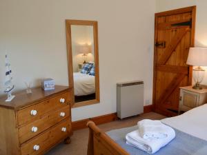 a bedroom with a bed and a dresser and a mirror at Limpet Cottage in Boulmer