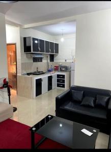a living room with a black couch and a kitchen at cosy appartement au Centre de la ville avec WIFI in Beni Mellal