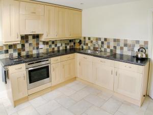 a kitchen with white cabinets and black counter tops at Bank End in Glenridding