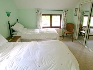 1 dormitorio con 2 camas, silla y ventana en Bank End, en Glenridding