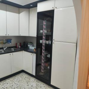 サレルノにあるCasa vacanza Arcangeliのキッチン(白いキャビネット、黒い冷蔵庫付)