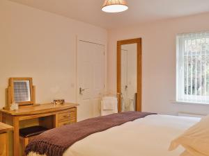 a bedroom with a bed and a desk and a mirror at Druimarbin Falls in Fort William