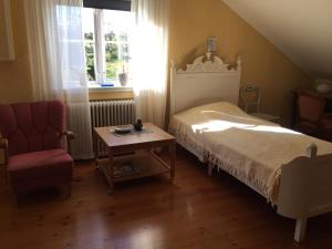 ein Schlafzimmer mit einem Bett, einem Stuhl und einem Tisch in der Unterkunft Sjöbredareds Gård in Hökerum