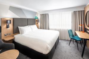 um quarto de hotel com uma cama grande e uma secretária em Holiday Inn Southampton Eastleigh, an IHG Hotel em Eastleigh