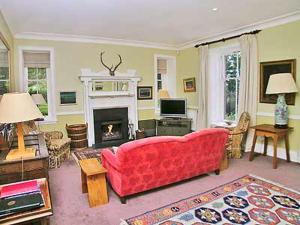 a living room with a red couch and a fireplace at Marwhin House - Swwr in Kirkpatrick Durham