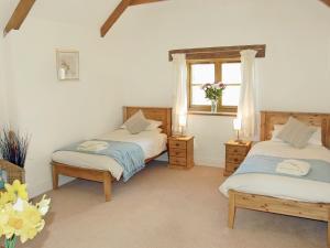 two twin beds in a room with a window at Polmear Barn in Camelford