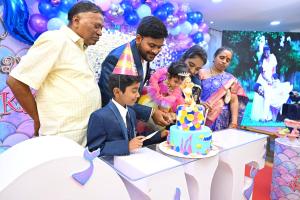 a man cutting a birthday cake with a boy at Hotel Hibiscus Tree- Bachupally in Hyderabad