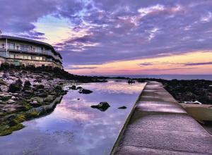 a beach with a building and a body of water at Foxy cottage nr Westward Ho! in Northam