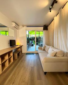 a living room with a white couch and a television at Évasion à deux, domaine prestigieux, jacuzzi et parking privés, piscine in Cannes