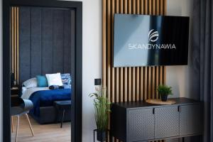 a living room with a tv on a wall at Domki i apartamenty Skandynawia in Dąbki