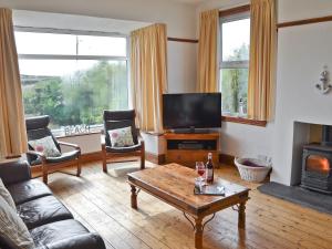 a living room with a couch and a tv and a table at Gwelfor in Trearddur