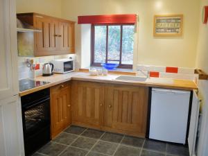 a kitchen with wooden cabinets and a sink and a microwave at No 2 Benar in Penmachno