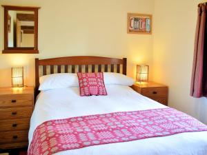 a bedroom with a bed with a pink blanket on it at No 2 Benar in Penmachno