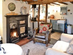 a living room with a chair and a fireplace at Cragg Cottage in Bouth