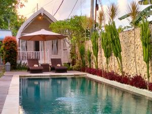 a swimming pool with two chairs and an umbrella at Wage cottage in Nusa Penida +28 photos