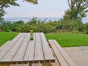 a wooden picnic table with a bottle and glasses on it at Solent View in Yarmouth