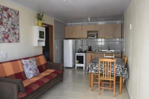 ein Wohnzimmer mit einem Sofa und einem Tisch sowie eine Küche in der Unterkunft Hospedagens São Borja RS in São Borja